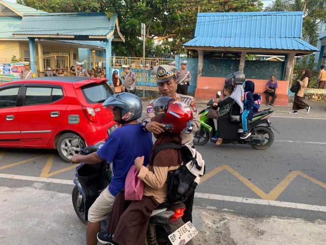 
					Sat Lantas Polres Bintan saat memberikan Helm Gratis kepada penumpang pengendara motor di Bintan, Kamis 25/7/2024 (Humas Polres Bintan)