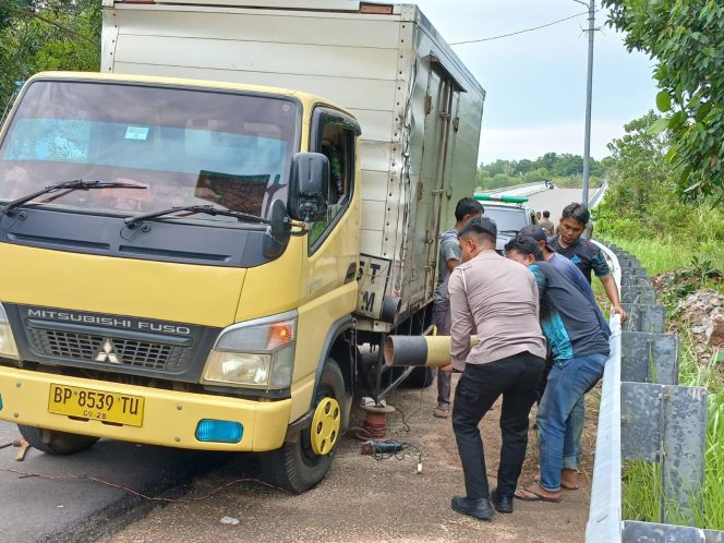 
					Anggota Satlantas Polresta Tanjungpinang saat mengevakuasi portal pembatas jembatan yang tersangkut di Lori Box, Senin (14/7/2025). (Nzl)