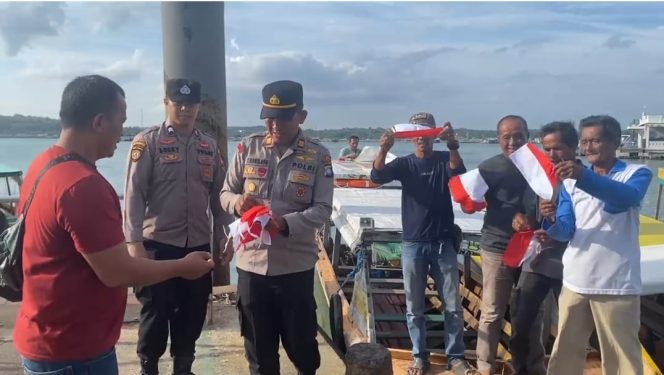Kapolsek Pelabuhan Sri Bintan Pura, Akp Yerry Manulang saat memberikam bendera kepada masyarakat di salah satu pelabuhan di Tanjungpinang, Sabtu (02/8/2025). (Humas Polres Tanjungpinang)