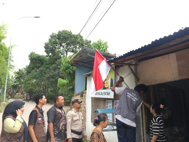 Sekretaris Lurah Tanjung Uma, Ahmad bersama masyarakat dan instansi terkait saat memasang bendera Merah Putih di salah satu rumah warga, Kamis (14/8/2025). (Istimewa)