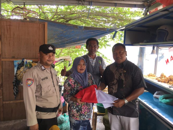 Sekretaris Lurah, saat membagikan bendera kepada masyarakat setempat, Kamis (14/8/2025). (Istimewa)