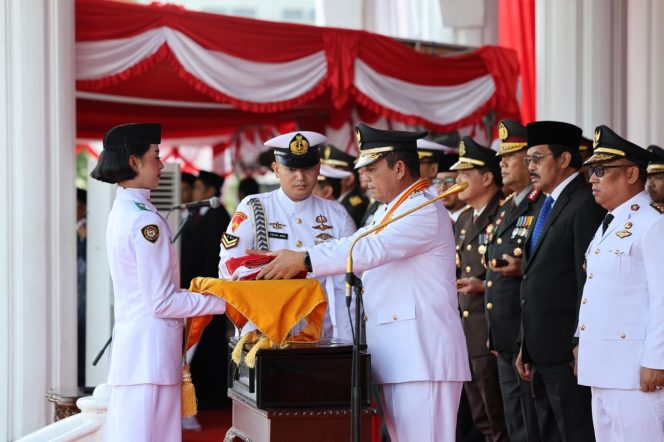 
					Gubernur Kepri, Ansar Ahmad saat memberikan baki Bendera Merah Putih kepada pembawa baki Tsaniyah Aqillah Muca I Kadek, di Halaman Depan Gedung Daerah Provinsi Kepri, Minggu (17/8/2025). (Diskominfo Kepri)
