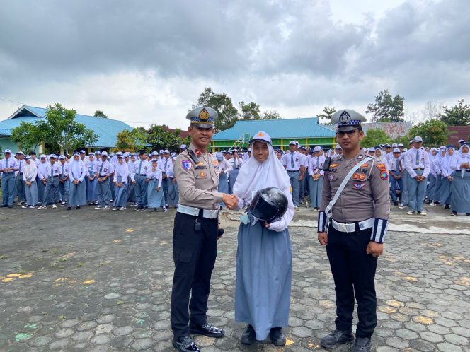 Anggota Satlantas Polres Bintan saat memberikan hadiah berupa helm.kepada para siswa di  kegiatan Police Go To, Senin (08/9/2025). (Humss Polres Bintan)