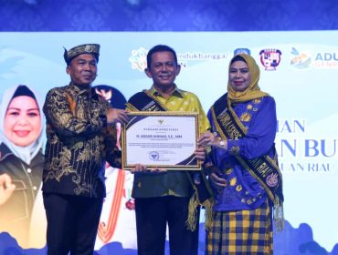 Menteri Kependudukan dan Pembangunan Keluarga RI, Wihaji, saat memberikan piagam penghargaan kepada Gubernur Kepri, Ansar Ahmad Ddidampingi  Istrinya Dewi Kulamasari Ansar di Pelataran Tugu Sirih, Tanjungpinang, Kamis (23/10/2025). (Diskominfo Kepri)