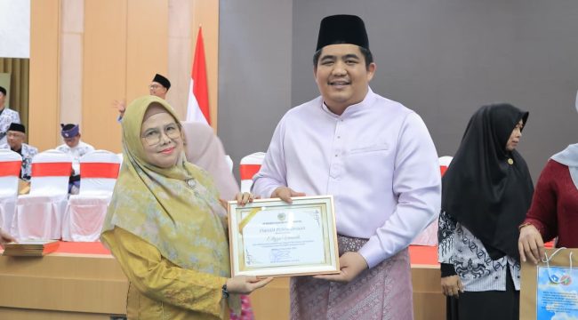 Bupati Roby saat menyerahkan penghargaan pada salah satu guru di Bintan.(Foto Humpro Pemkab Bintan)